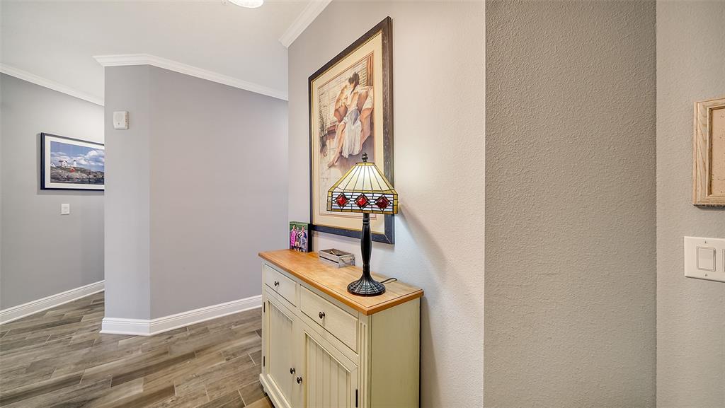 A hallway features wood-look tile flooring, gray walls, a wooden console table, and a stained-glass lamp — 7910 34TH AVENUE W UNIT 203, BRADENTON, FL
