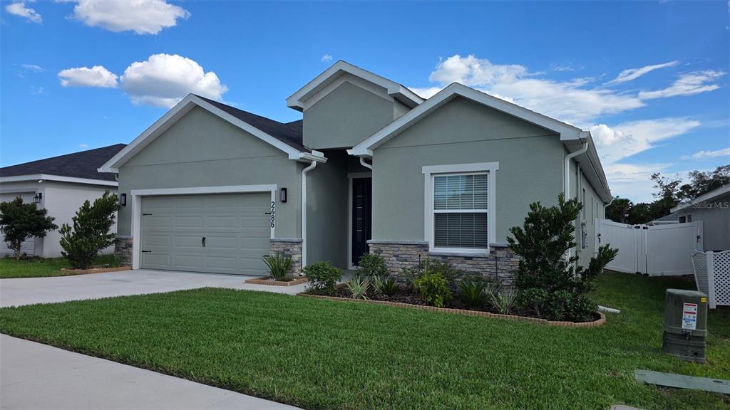 A single-story house with a two-car garage, stone accents, and a green lawn — 2486 MATTERHORN TRAIL, DAVENPORT, FL