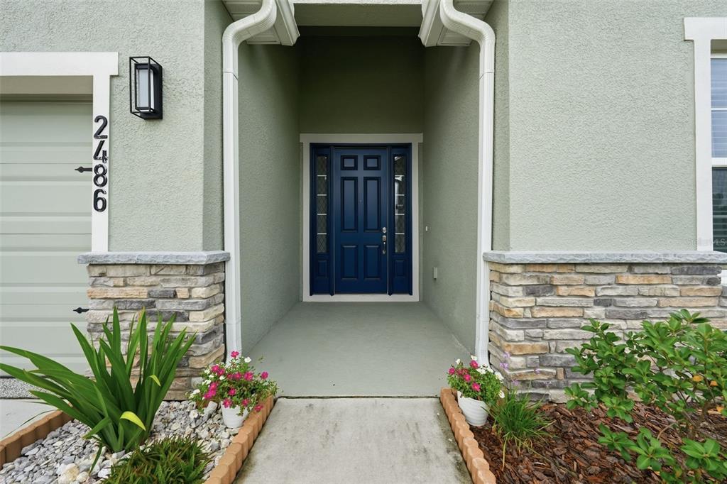 A front entryway features a blue door with sidelights, stone veneer accents, and a concrete path — 2486 MATTERHORN TRAIL, DAVENPORT, FL