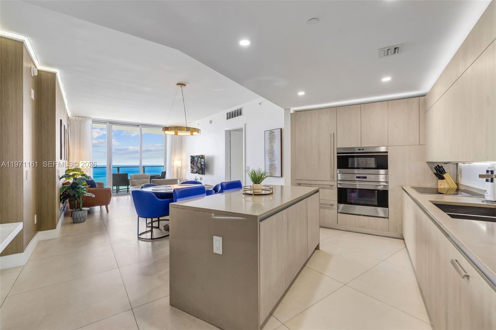 A modern kitchen with light wood cabinets and a central island overlooks a dining area — 4111 S Ocean Dr # 3706, Hollywood FL 33019, HOLLYWOOD, FL