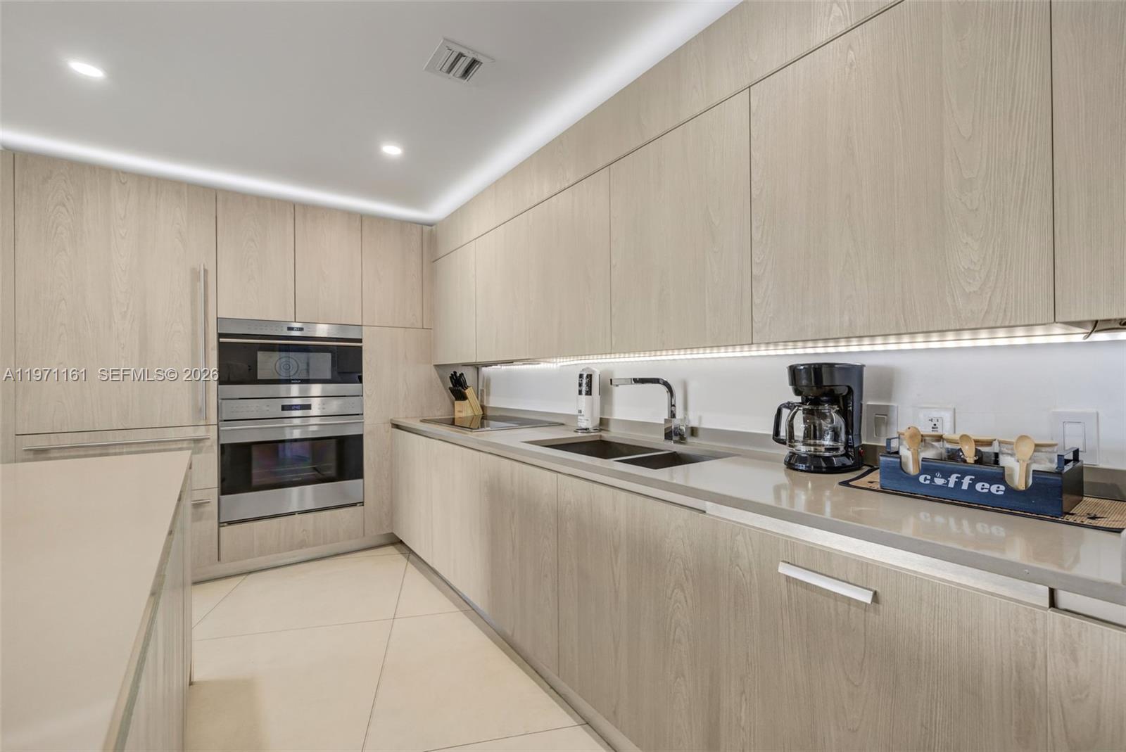 A modern kitchen features light wood cabinetry, stainless steel appliances, and a stone countertop — 4111 S Ocean Dr # 3706, Hollywood FL 33019, HOLLYWOOD, FL