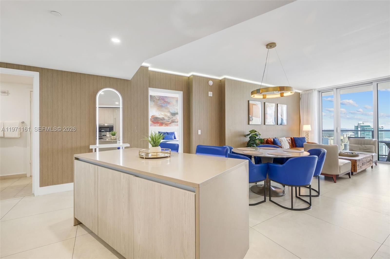 A modern open-plan living and dining area features a kitchen island and blue chairs — 4111 S Ocean Dr # 3706, Hollywood FL 33019, HOLLYWOOD, FL