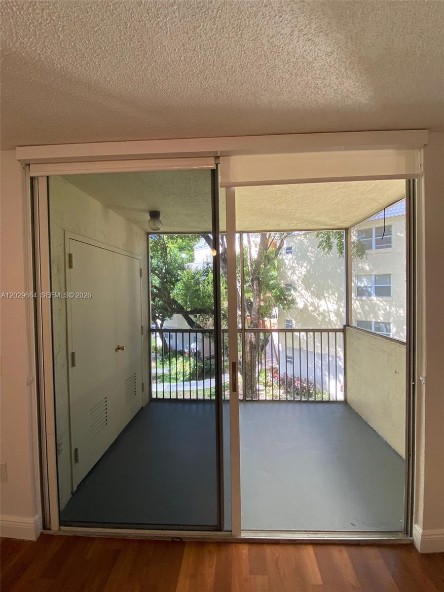 A balcony with a metal railing and a storage closet is viewed through sliding glass doors — 8323 Lake Dr # 302, Doral FL 33166, DORAL, FL