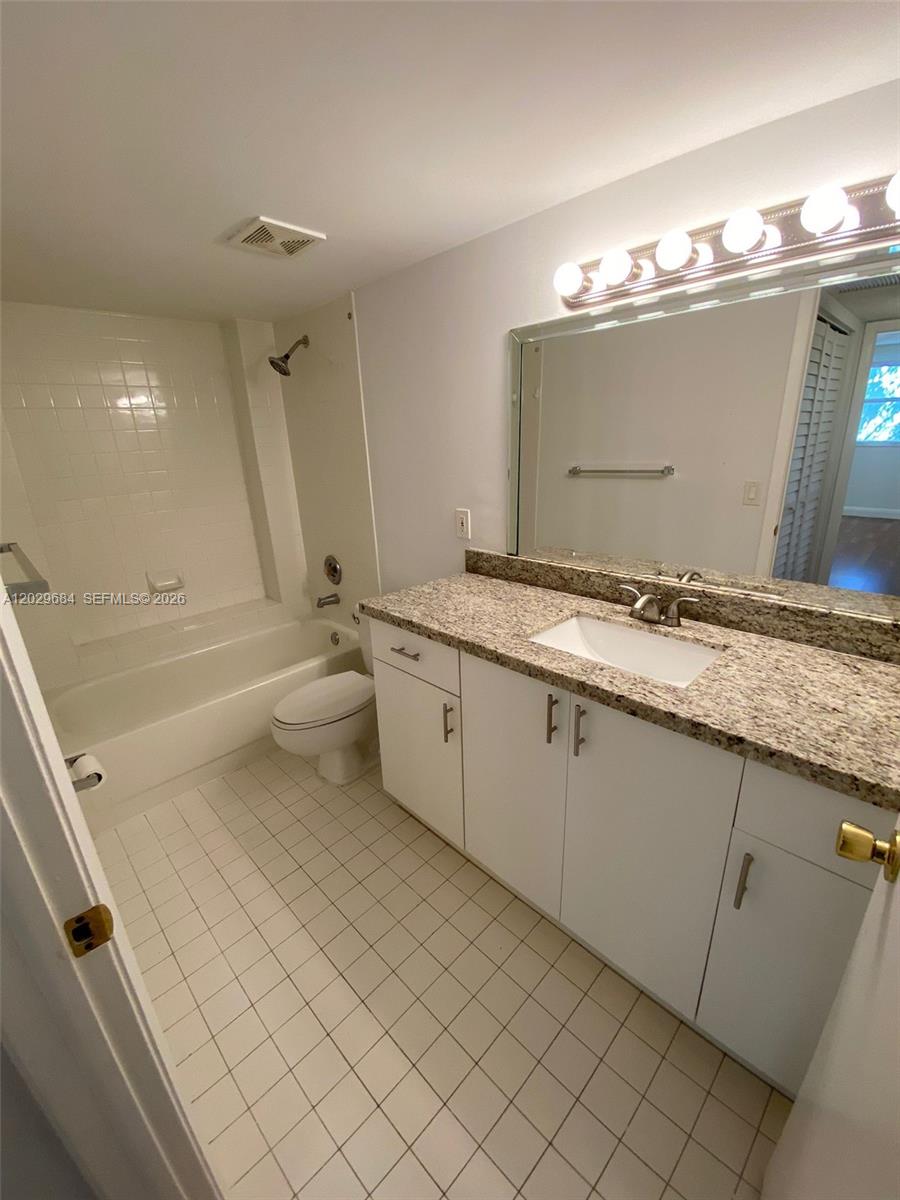 A bathroom features a white vanity with a granite countertop, a mirror, and a tub-shower — 8323 Lake Dr # 302, Doral FL 33166, DORAL, FL