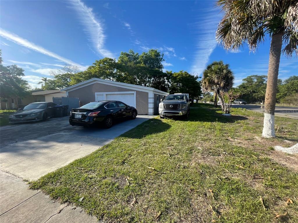 A single-story house with a concrete driveway, two parked cars, and a palm tree — 1820 BARNA AVENUE, TITUSVILLE, FL