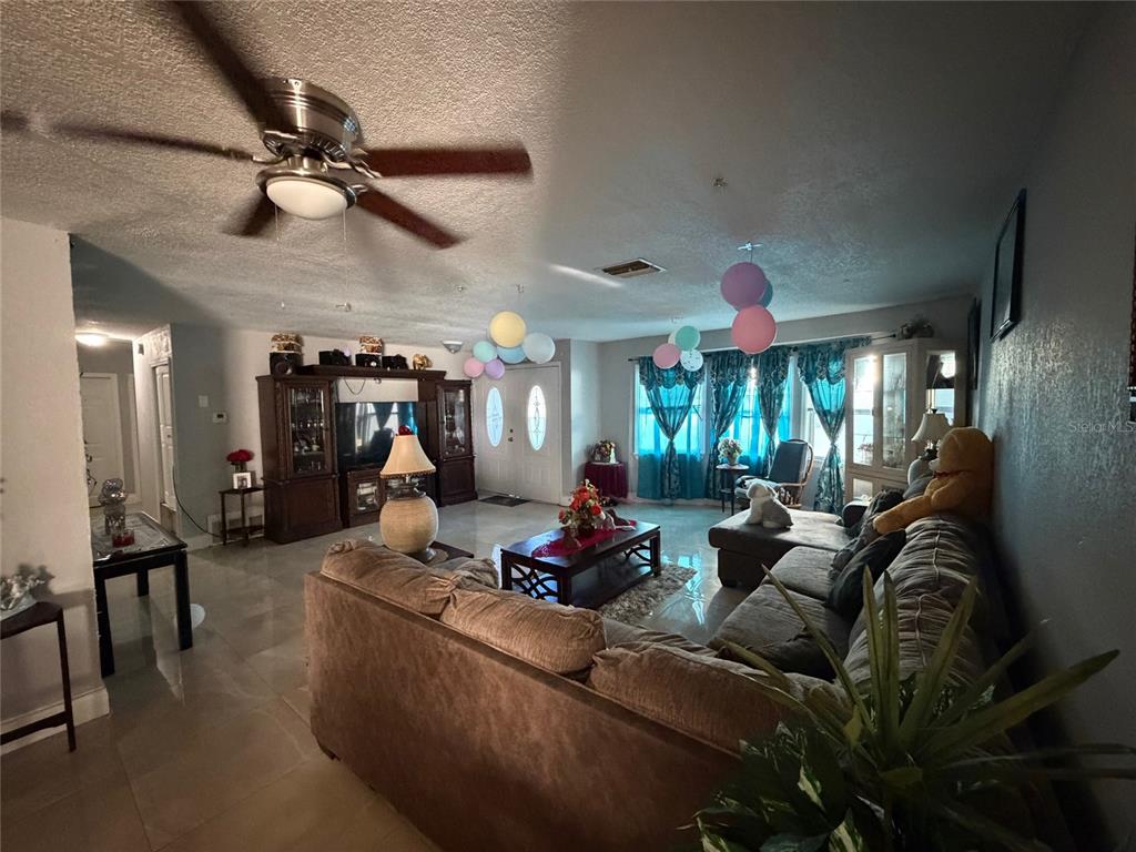 A living room features tile flooring, a ceiling fan, and a large sectional sofa — 1820 BARNA AVENUE, TITUSVILLE, FL