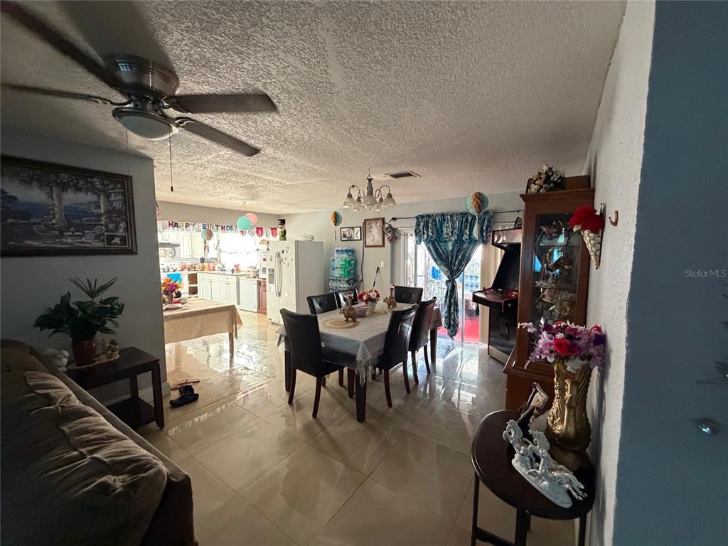 A dining area with a table and chairs sits adjacent to a kitchen and living space — 1820 BARNA AVENUE, TITUSVILLE, FL