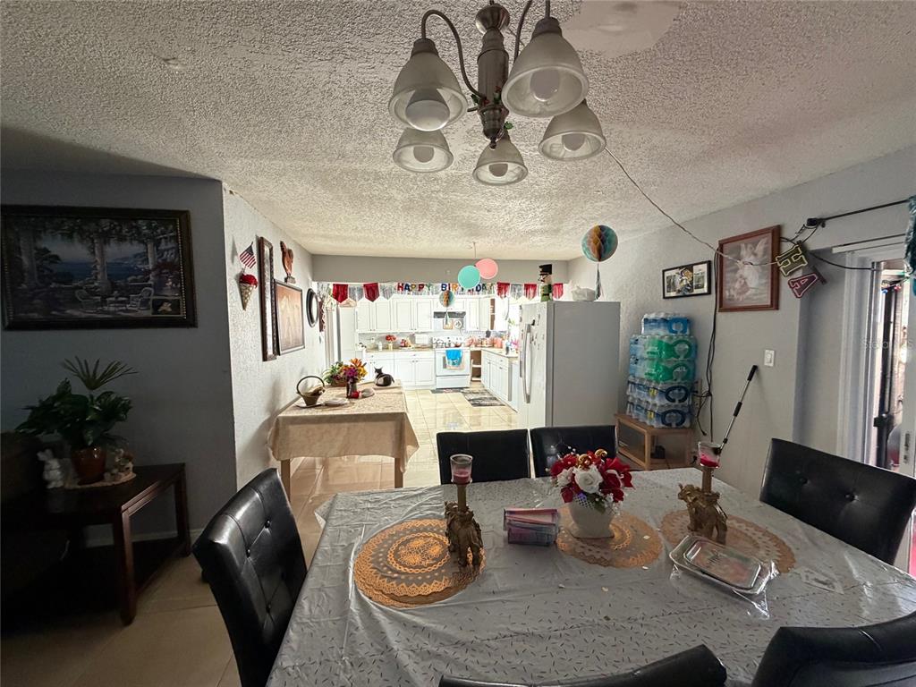 A dining room with a table and chairs leads into a kitchen with white cabinets — 1820 BARNA AVENUE, TITUSVILLE, FL