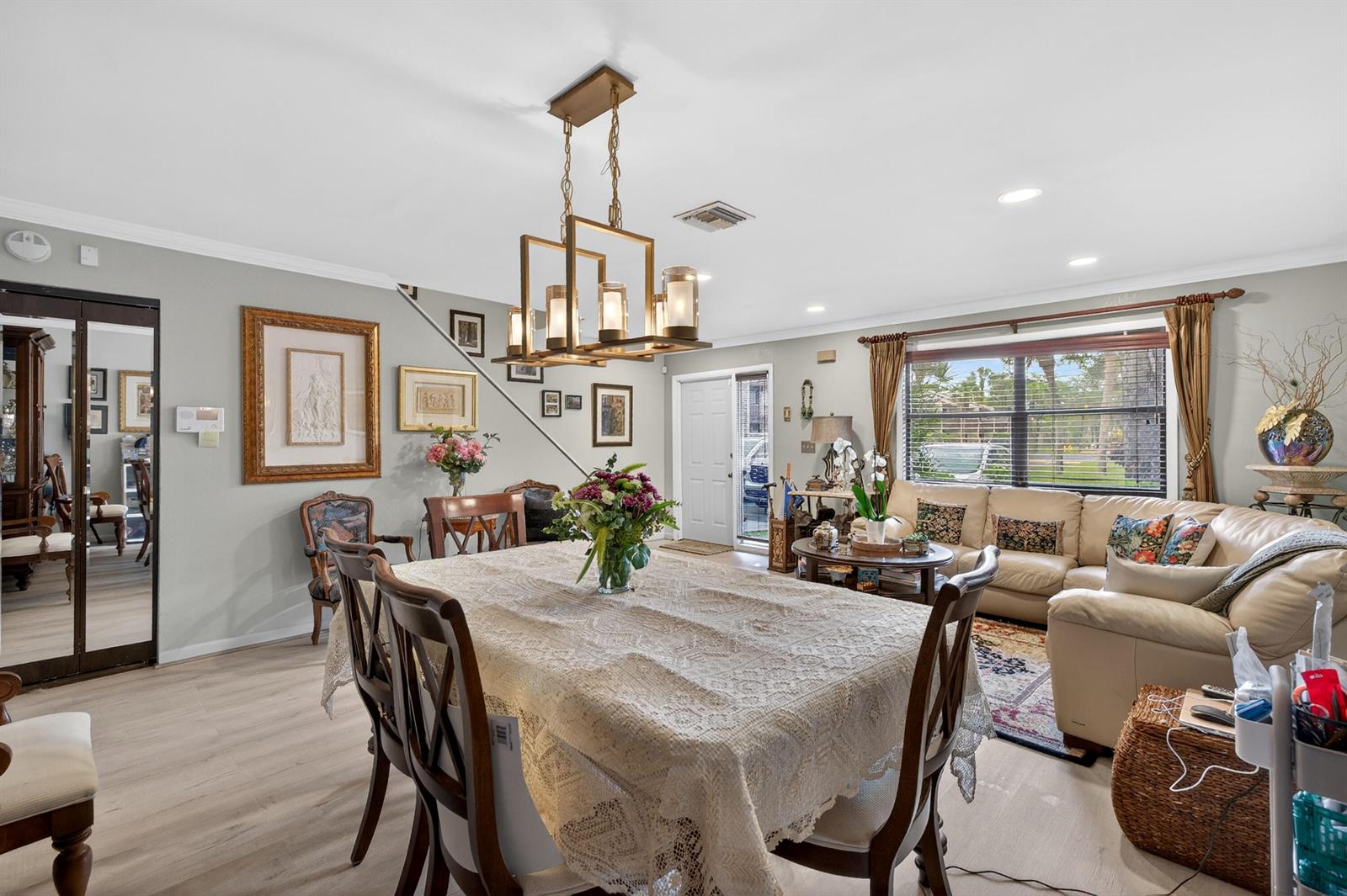 A dining area with a lace-covered table and chandelier flows into a living room space — 837 NW 47th Street, Deerfield Beach FL 33064, DEERFIELD BEACH, FL