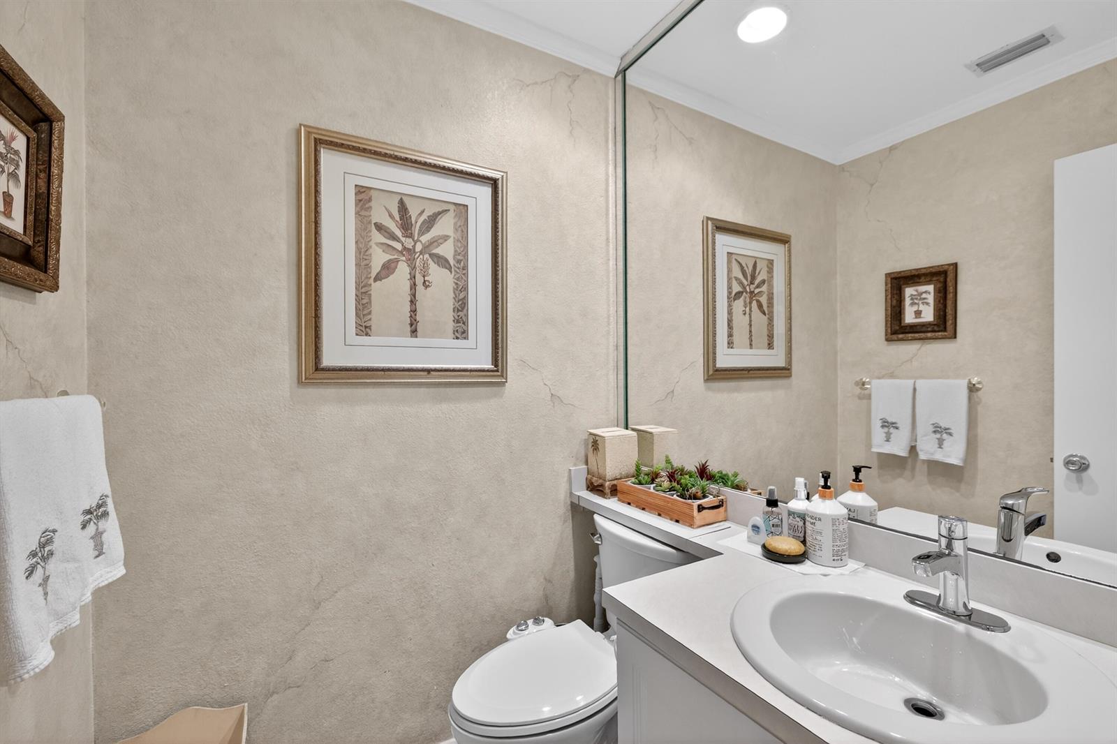 A bathroom features a vanity with a white sink, a toilet, and palm-themed wall art — 837 NW 47th Street, Deerfield Beach FL 33064, DEERFIELD BEACH, FL