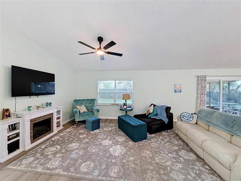 A living room features a fireplace, a large area rug, and a ceiling fan — 706 OLD CREEK COURT, SANFORD, FL