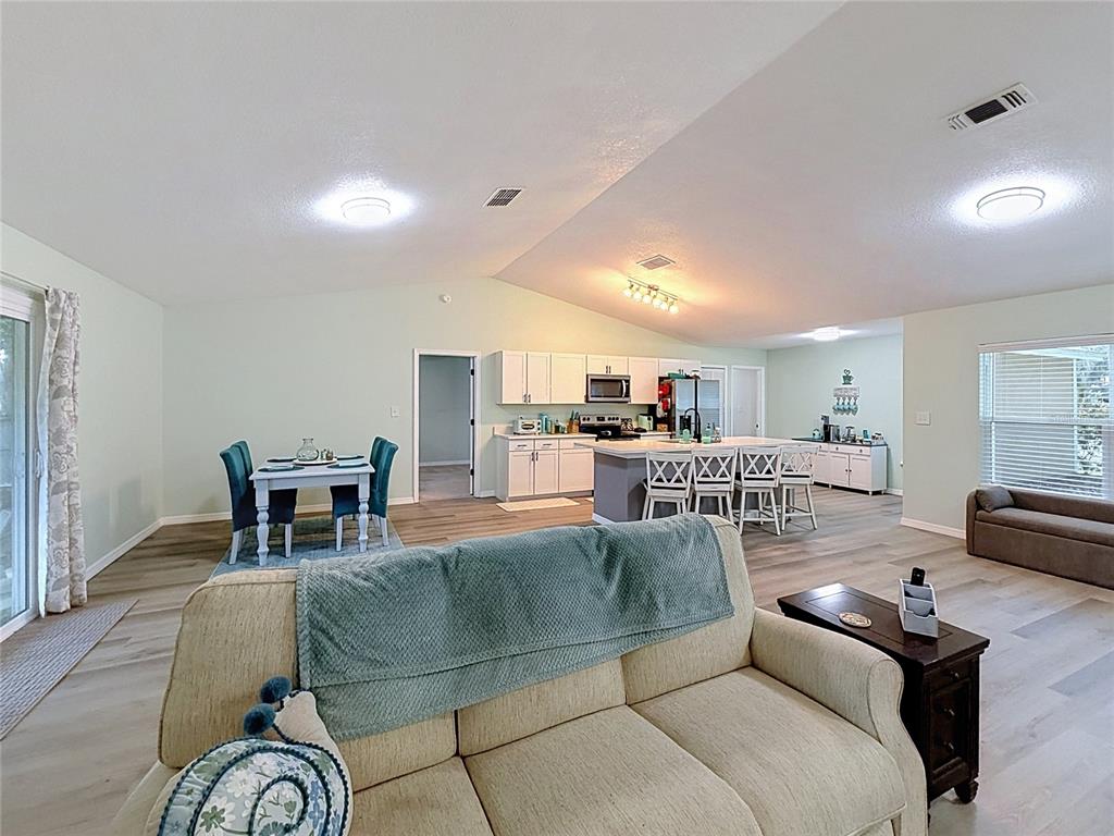 An open-concept living area features a kitchen with an island, dining space, and light flooring — 706 OLD CREEK COURT, SANFORD, FL
