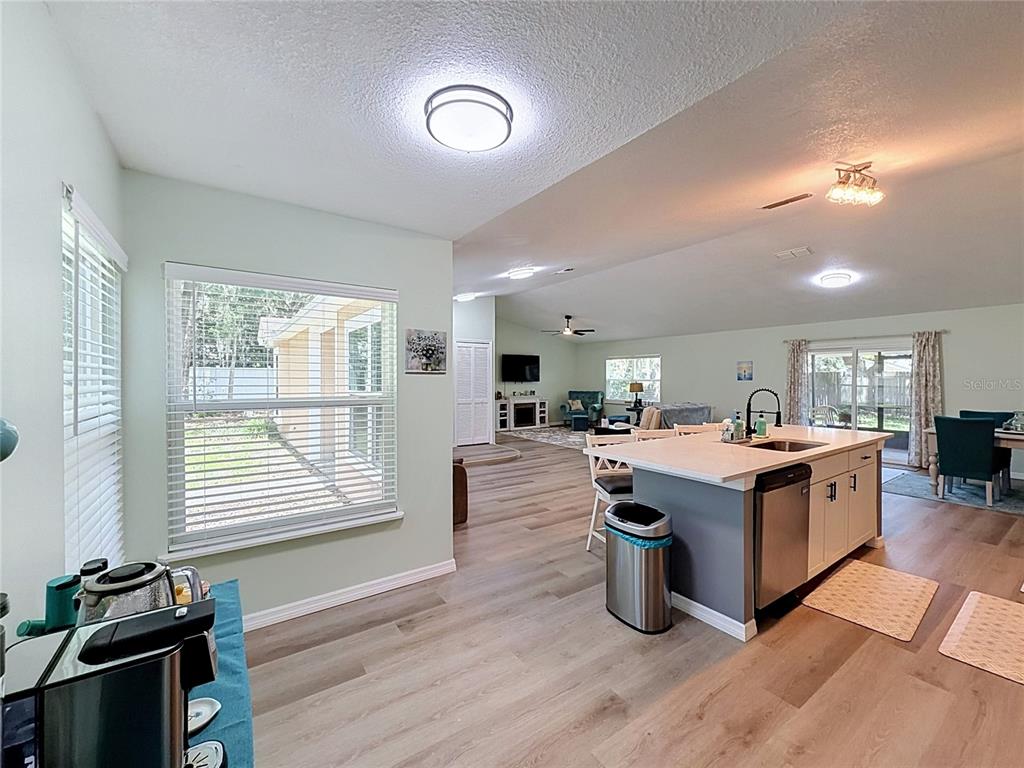 An open-concept kitchen and living area features light wood flooring and a central island — 706 OLD CREEK COURT, SANFORD, FL