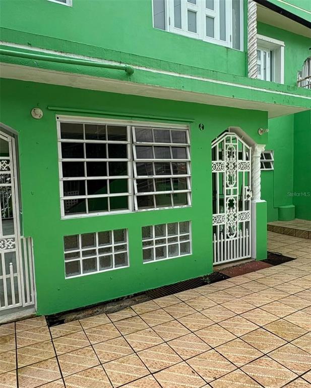 A bright green exterior wall features a large window with security bars and a decorative gate — LA BARRA 105 F, CAGUAS, PR
