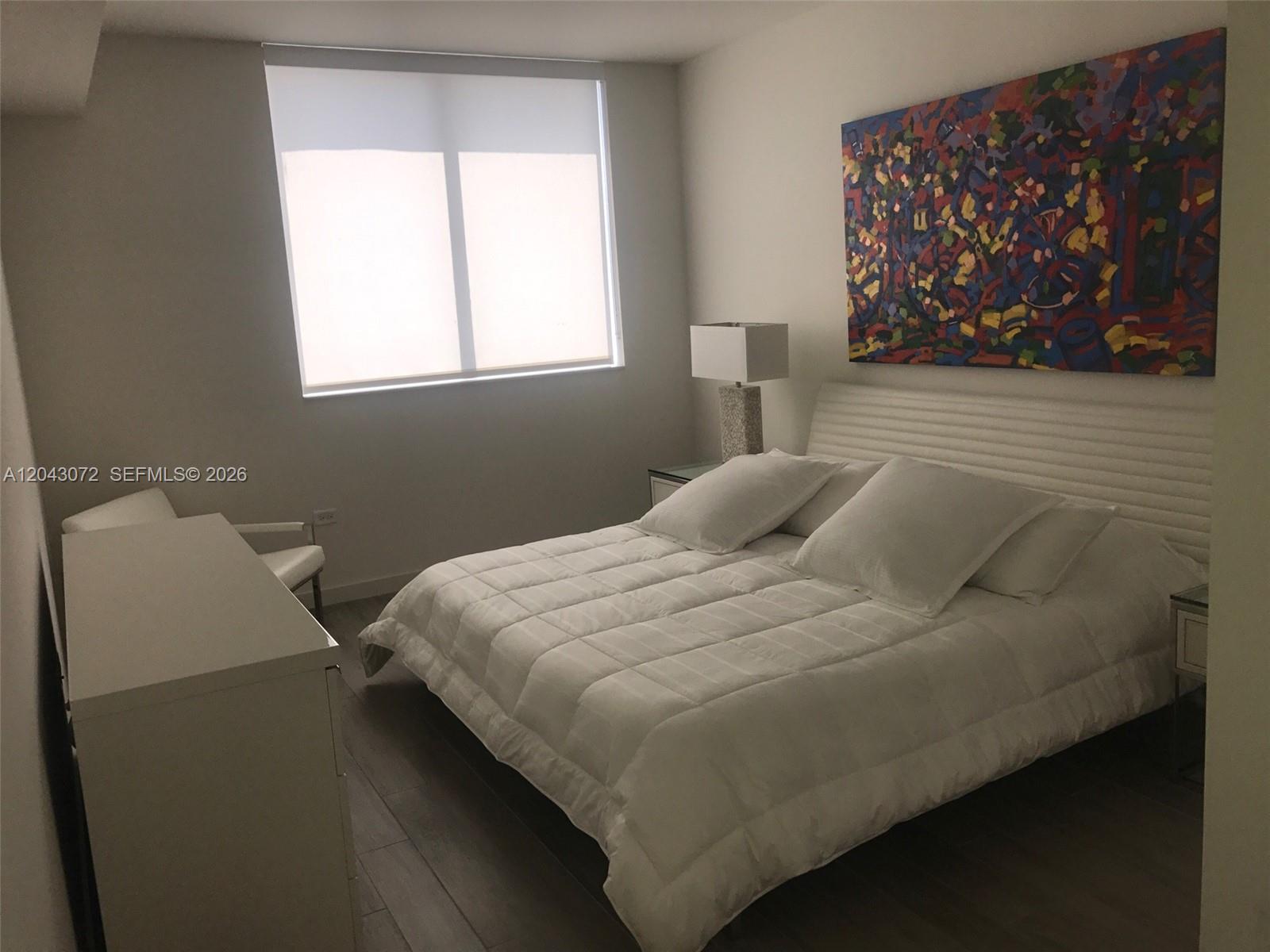 A bedroom features a white bed, a large abstract painting, and a window with blinds — 999 SW 1st Ave # 2806, Miami FL 33130, MIAMI, FL