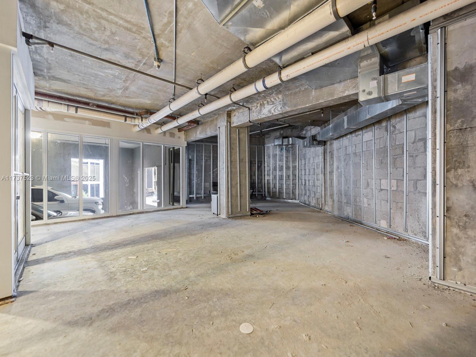 An unfinished commercial space features exposed concrete ceilings, metal wall studs, and large glass windows — 170 SE 14th St, Miami FL 33131, MIAMI, FL