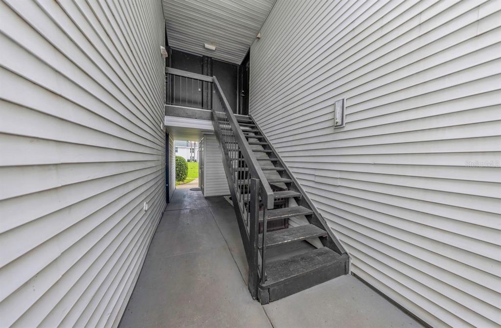 An exterior staircase leads to an upper-level landing between two buildings with white siding — 643 HAVEN PLACE UNIT 643, TARPON SPRINGS, FL