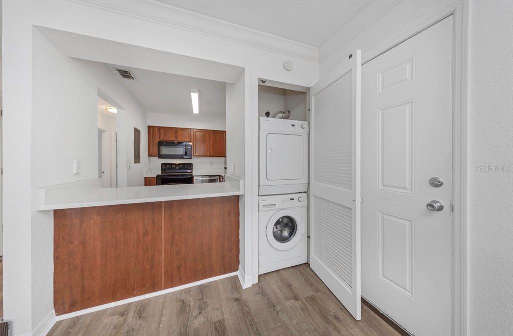 A kitchen with a breakfast bar and a stacked washer and dryer unit — 643 HAVEN PLACE UNIT 643, TARPON SPRINGS, FL