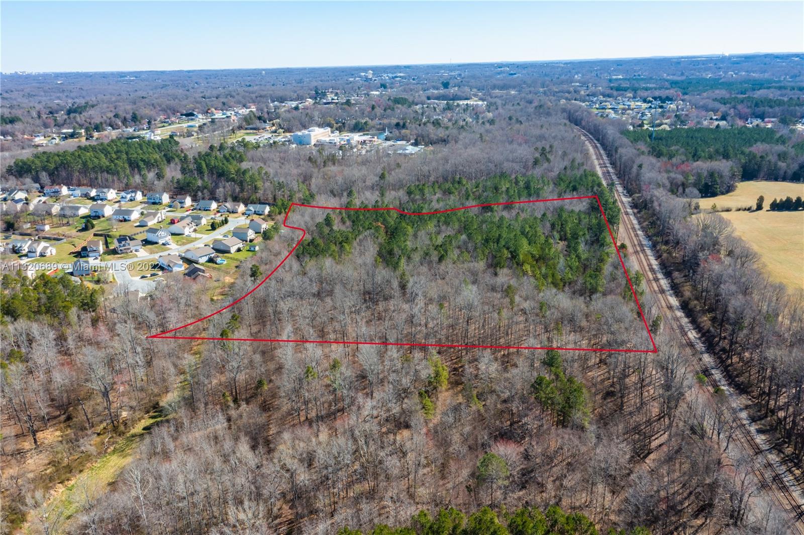 An aerial view shows a wooded plot of land outlined in red near a railroad track — 0 Coral Lane, NC 27360, NC