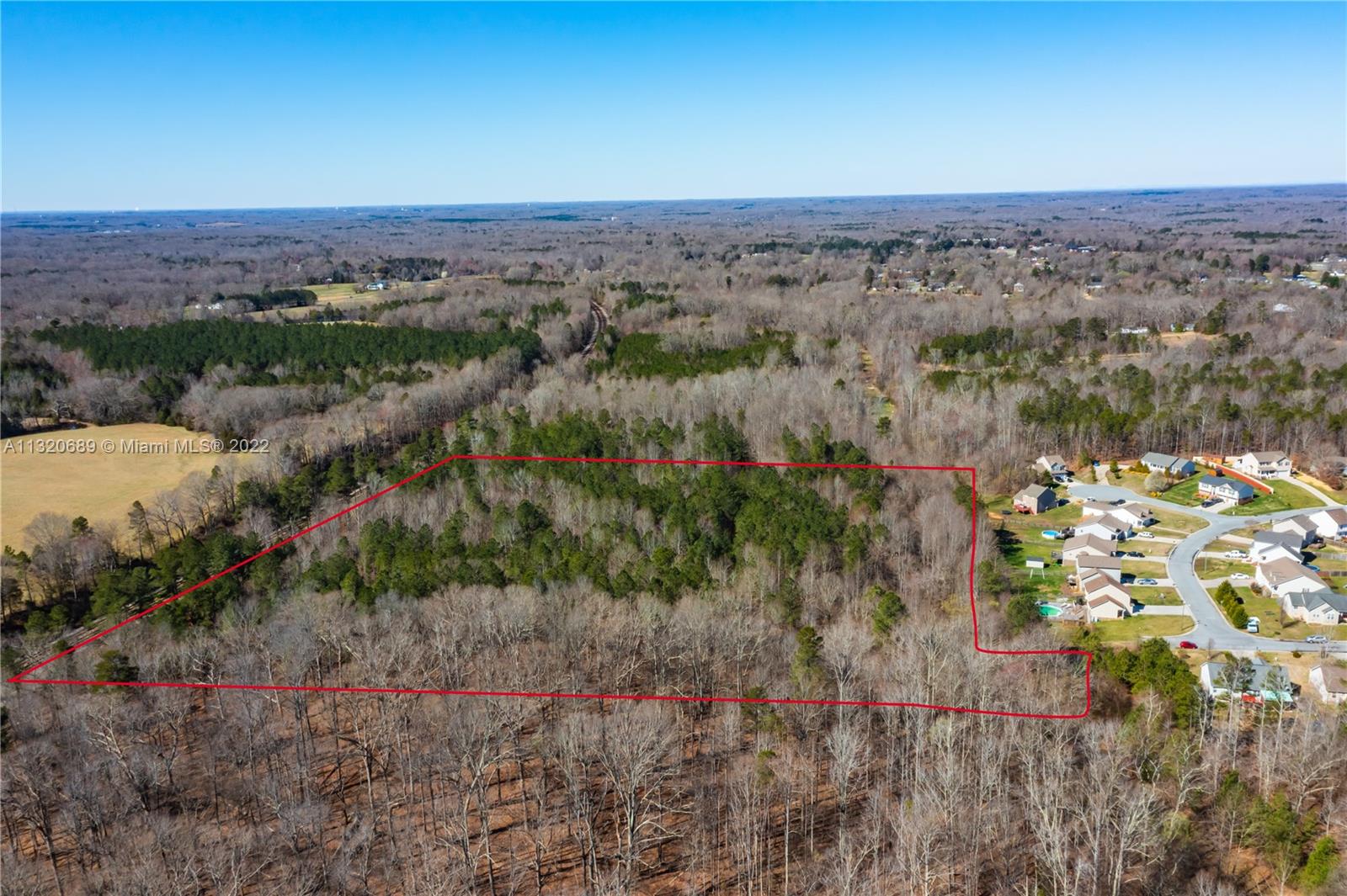 An aerial view shows a wooded plot of land outlined in red next to a neighborhood — 0 Coral Lane, NC 27360, NC