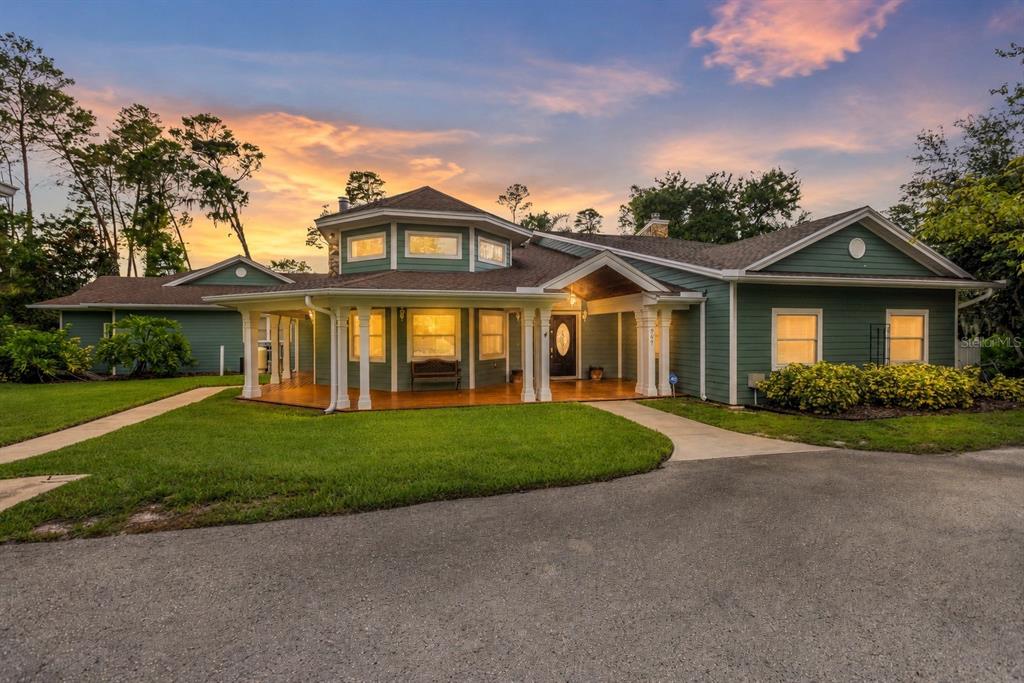 A green single-story house with a wrap-around porch and a central elevated roof section — 967 PINE HILL ROAD, PALM HARBOR, FL