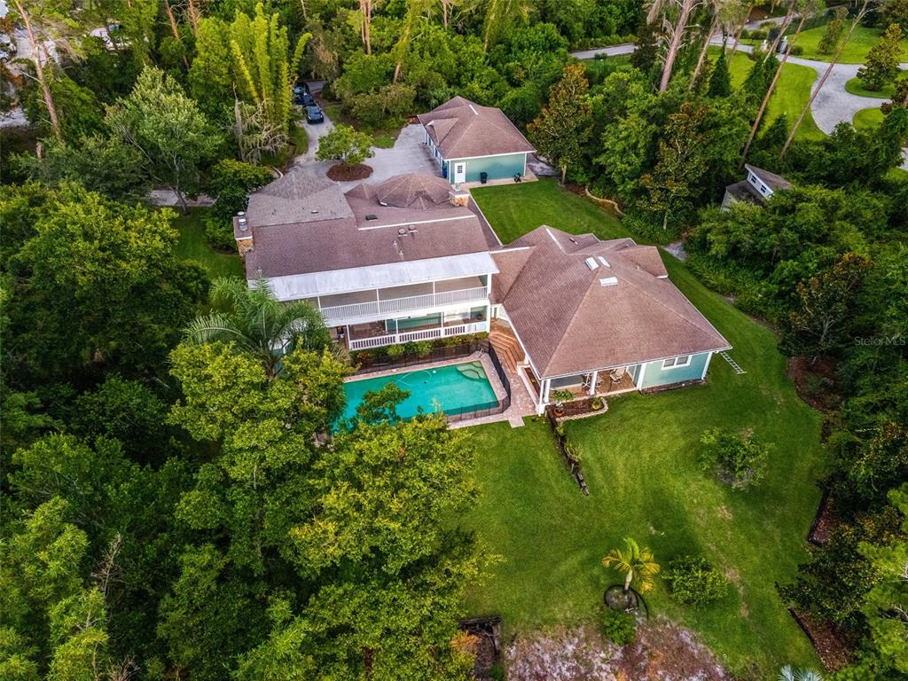 An aerial view shows a house with a swimming pool, a detached garage, and trees — 967 PINE HILL ROAD, PALM HARBOR, FL