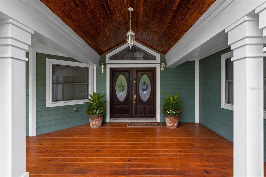 A covered front porch features wood decking, a wood-paneled ceiling, and double doors — 967 PINE HILL ROAD, PALM HARBOR, FL