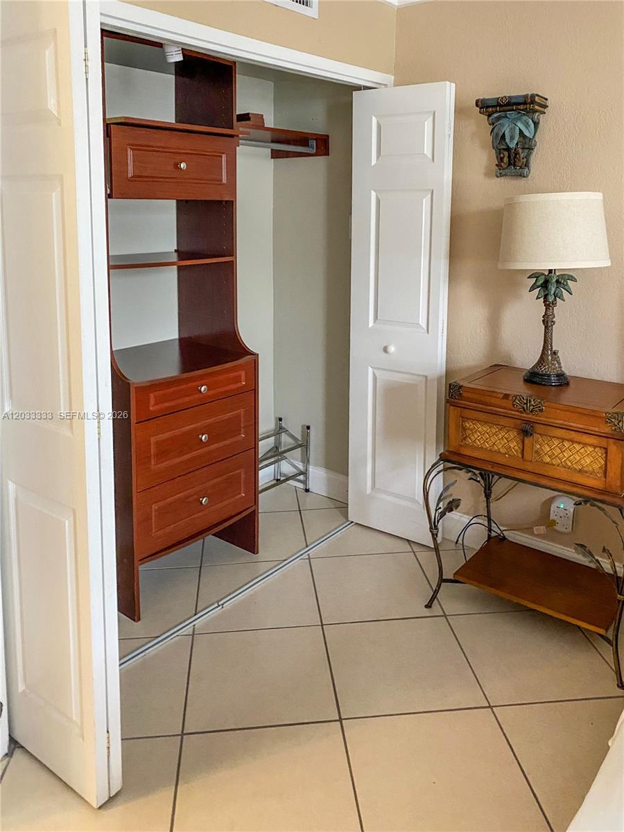 A kitchen features wood cabinets, granite countertops, stainless steel appliances, and light-colored tile flooring — 9225 Collins Ave # 1206, Surfside FL 33154, SURFSIDE, FL