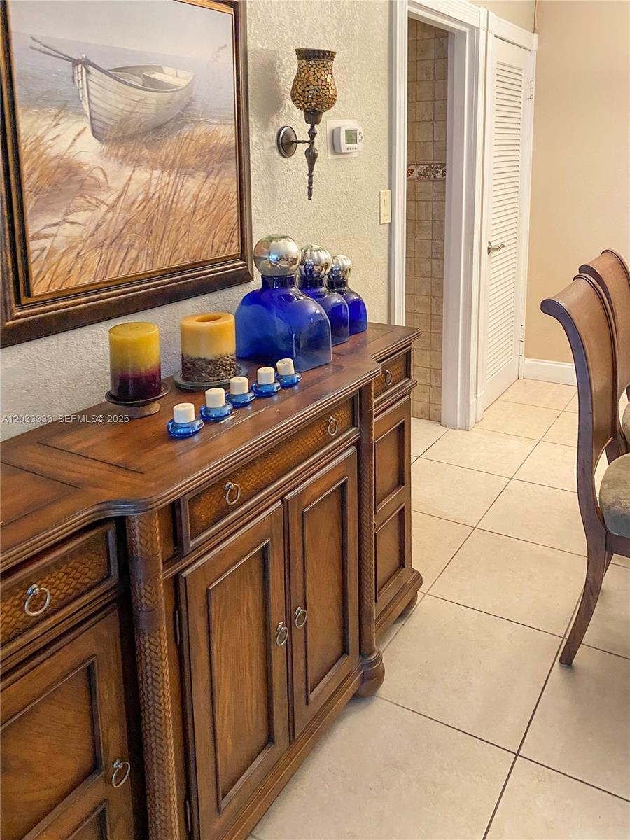 A dining area with a glass table overlooks a living room featuring mirrored walls — 9225 Collins Ave # 1206, Surfside FL 33154, SURFSIDE, FL