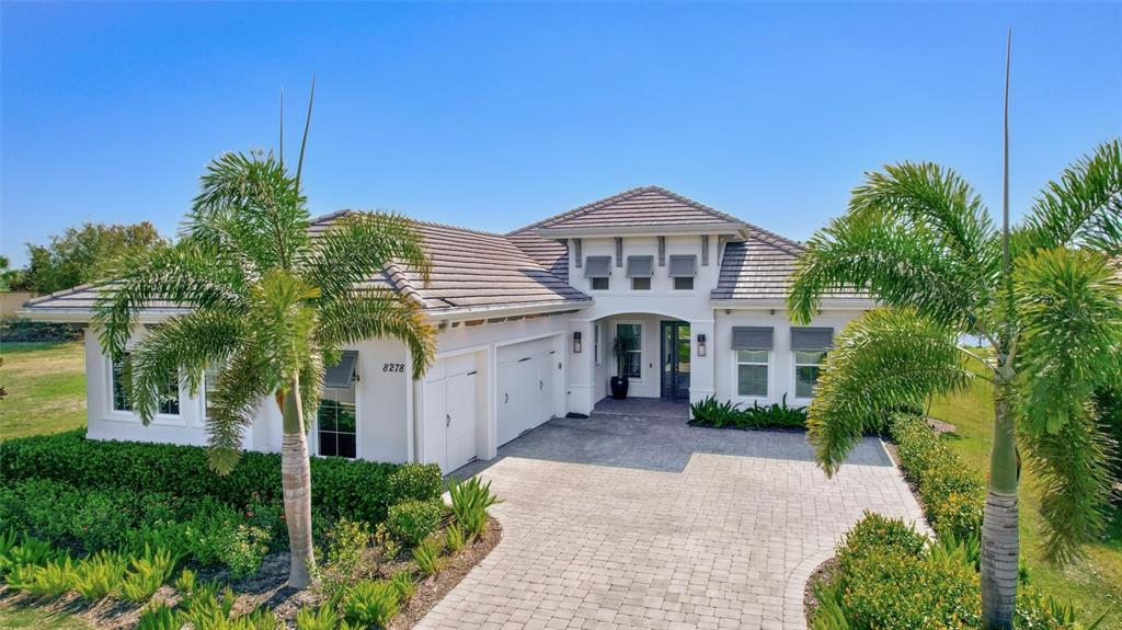A single-story house with a tiled roof, white stucco exterior, and a paved driveway — 8278 PAVIA WAY, BRADENTON, FL