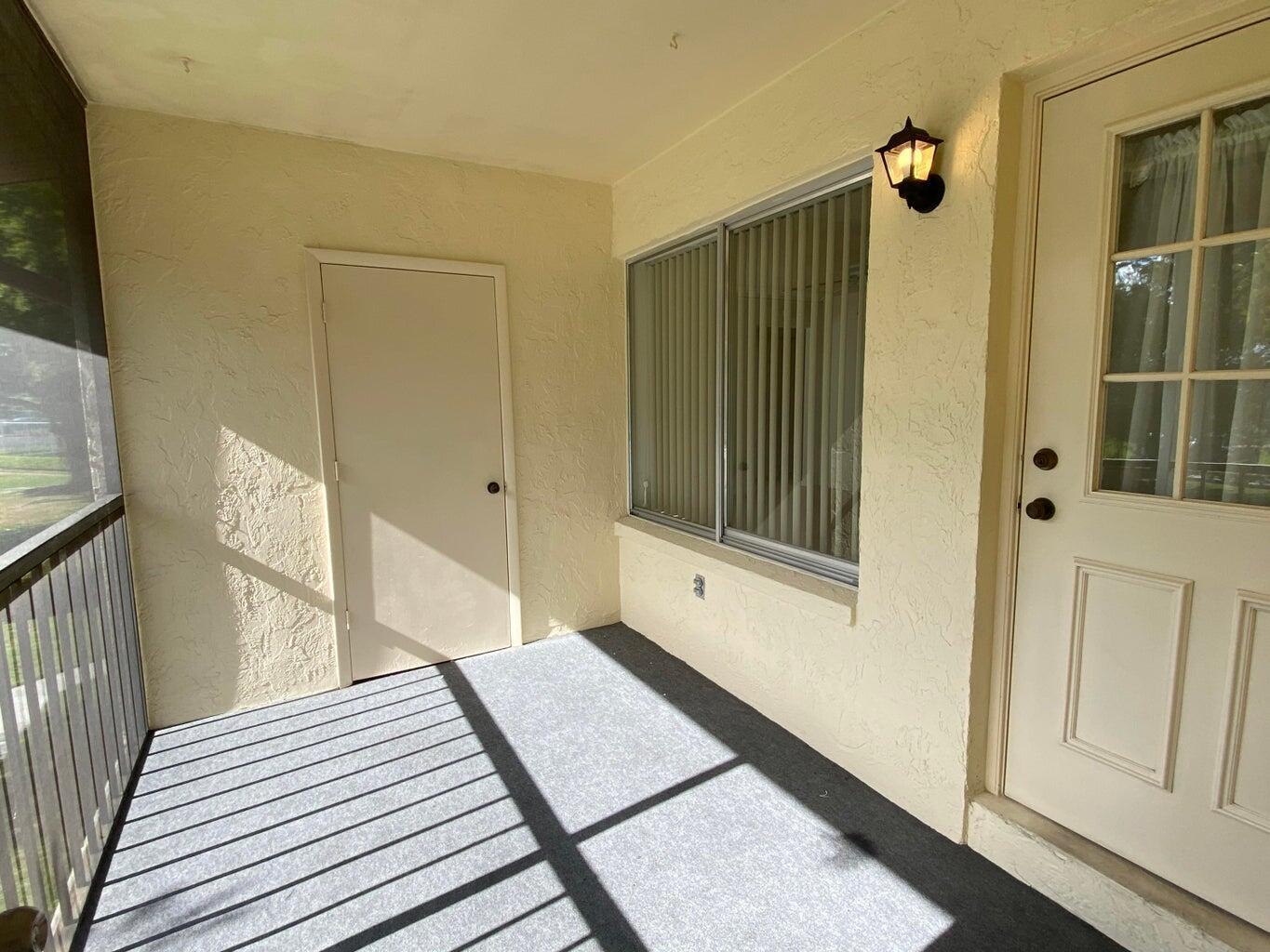 A covered patio features a gray carpeted floor, a storage closet, and a glass-paneled door — 4835 Sable Pine Circle # A2, West Palm Beach FL 33417, WEST PALM BEACH, FL