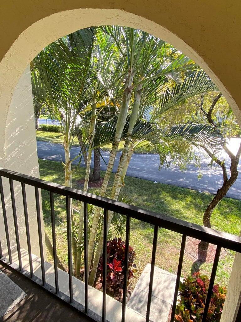 A view of palm trees and a road seen through an arched balcony opening — 4835 Sable Pine Circle # A2, West Palm Beach FL 33417, WEST PALM BEACH, FL