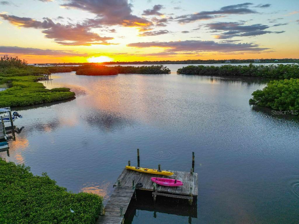 A two-story house with beige siding, a metal roof, and a front staircase leading upstairs — 6511 BAYSHORE ROAD, PALMETTO, FL
