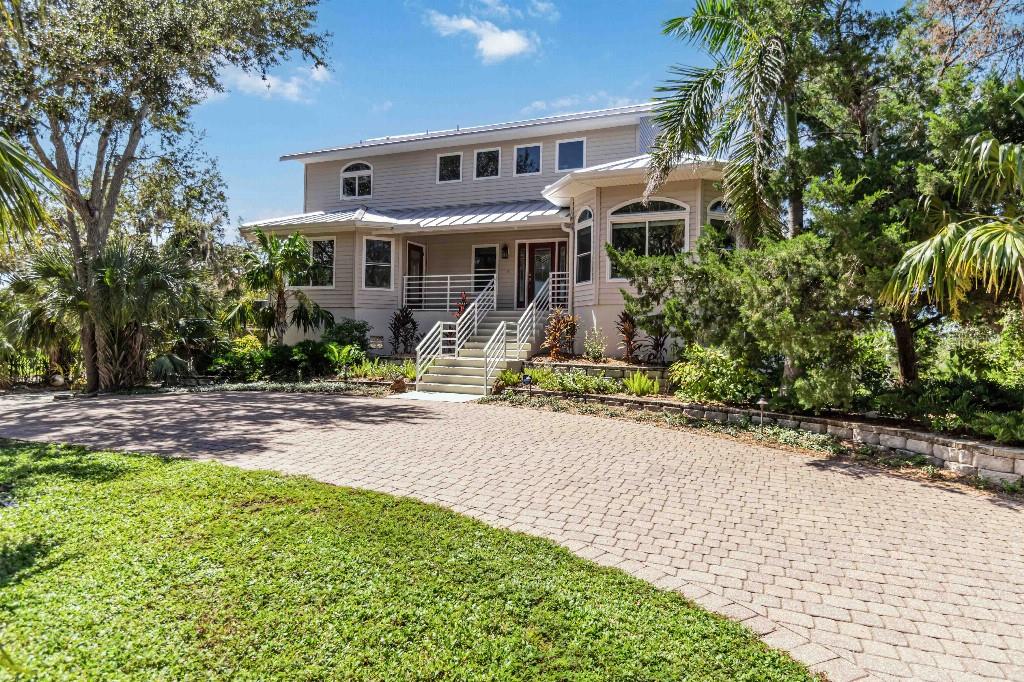 A two-story house with light-colored siding, a metal roof, and a paved driveway — 6511 BAYSHORE ROAD, PALMETTO, FL