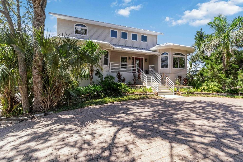 A two-story house with light-colored siding, a metal roof, and a paved circular driveway — 6511 BAYSHORE ROAD, PALMETTO, FL