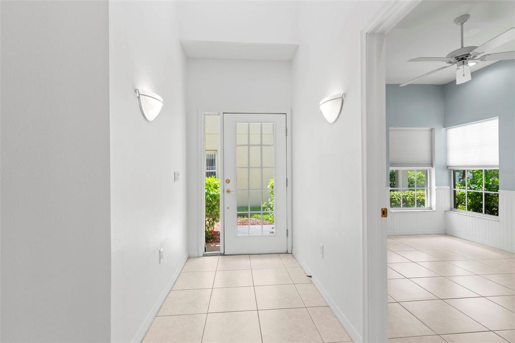 A bright entryway with white walls, tiled floors, and a glass-paneled front door — 11117 KAPOK GRAND CIRCLE, MADEIRA BEACH, FL