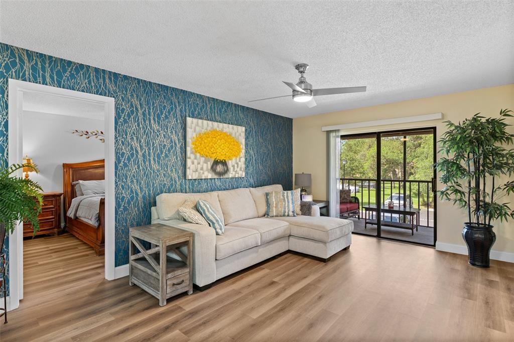 A living room features a blue accent wall, a beige sectional sofa, and sliding glass doors — 19505 QUESADA AVENUE UNIT VV201, PORT CHARLOTTE, FL
