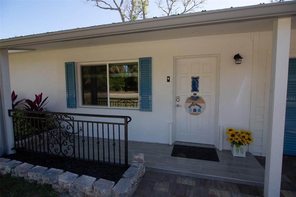 A white house exterior features a front porch with a metal railing and a door — 4311 126TH STREET W, CORTEZ, FL