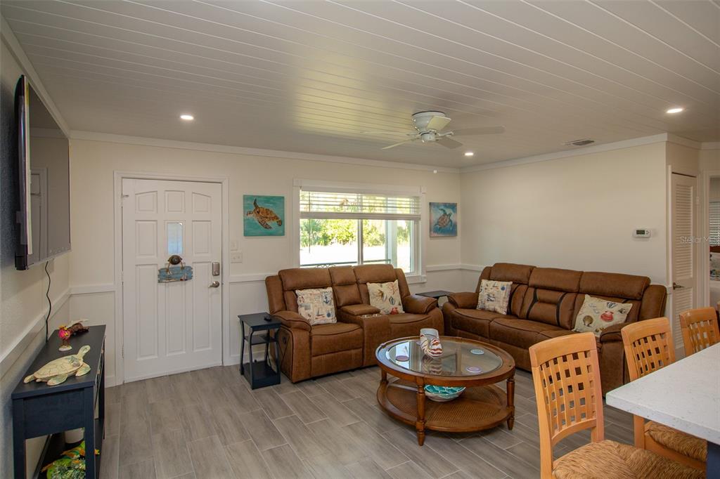 A living room with brown leather sofas, a glass coffee table, and wood-plank ceiling — 4311 126TH STREET W, CORTEZ, FL