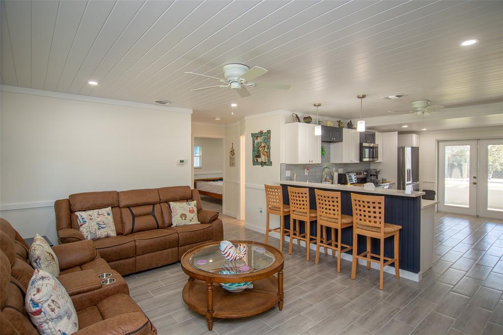 An open-concept living room and kitchen with wood-plank ceilings, tile floors, and a breakfast bar — 4311 126TH STREET W, CORTEZ, FL