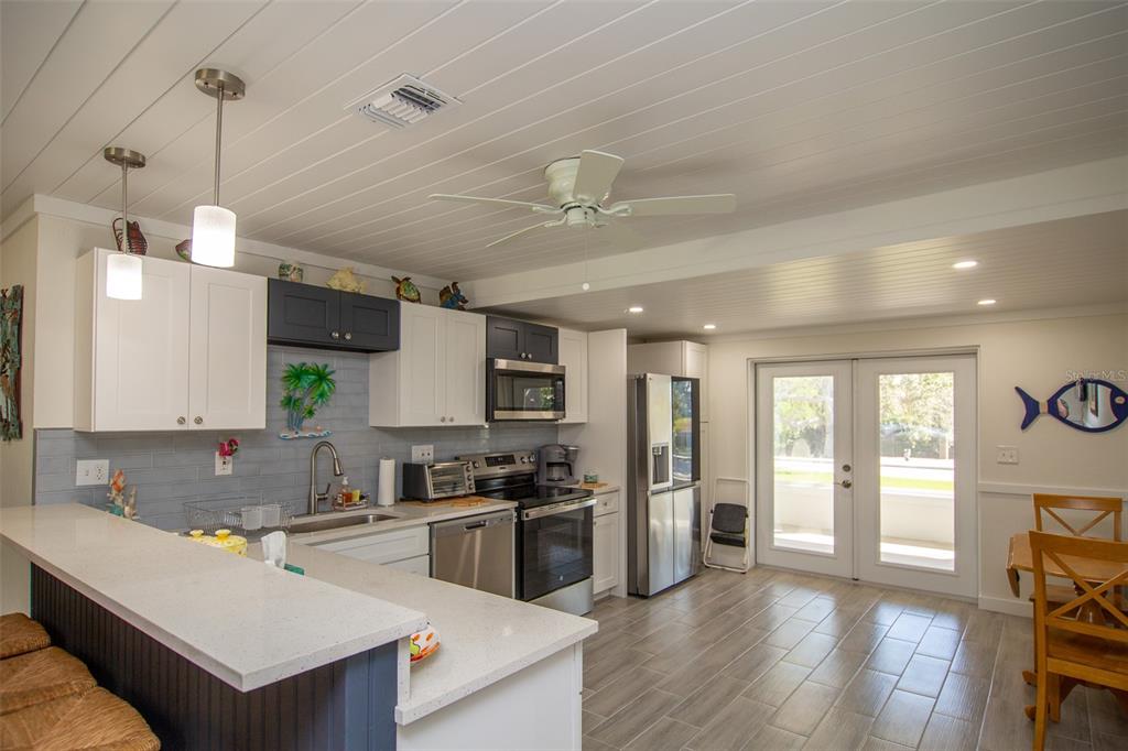 A kitchen with white and dark blue cabinets, stainless steel appliances, and a breakfast bar — 4311 126TH STREET W, CORTEZ, FL