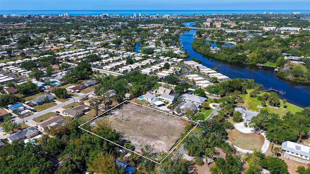 An aerial view shows a vacant, rectangular lot outlined in white within a residential neighborhood — 2424 ASHTON ROAD, SARASOTA, FL