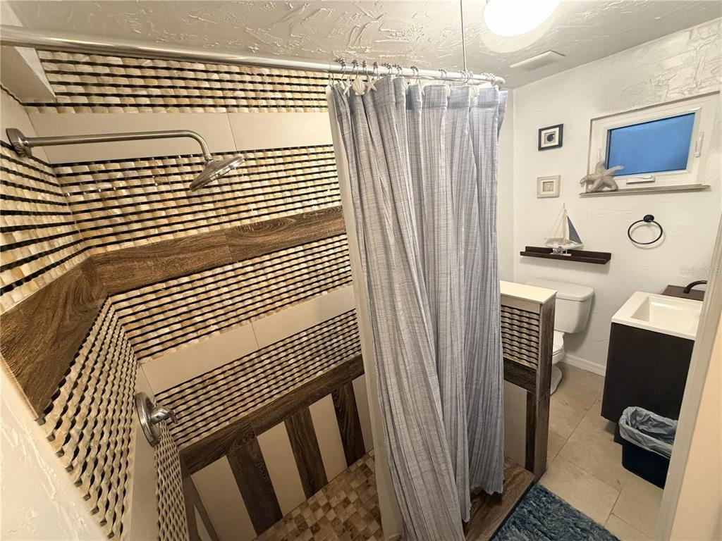 A bathroom features a walk-in shower with decorative tile, a toilet, and a vanity — 1707 W COMANCHE AVENUE, TAMPA, FL
