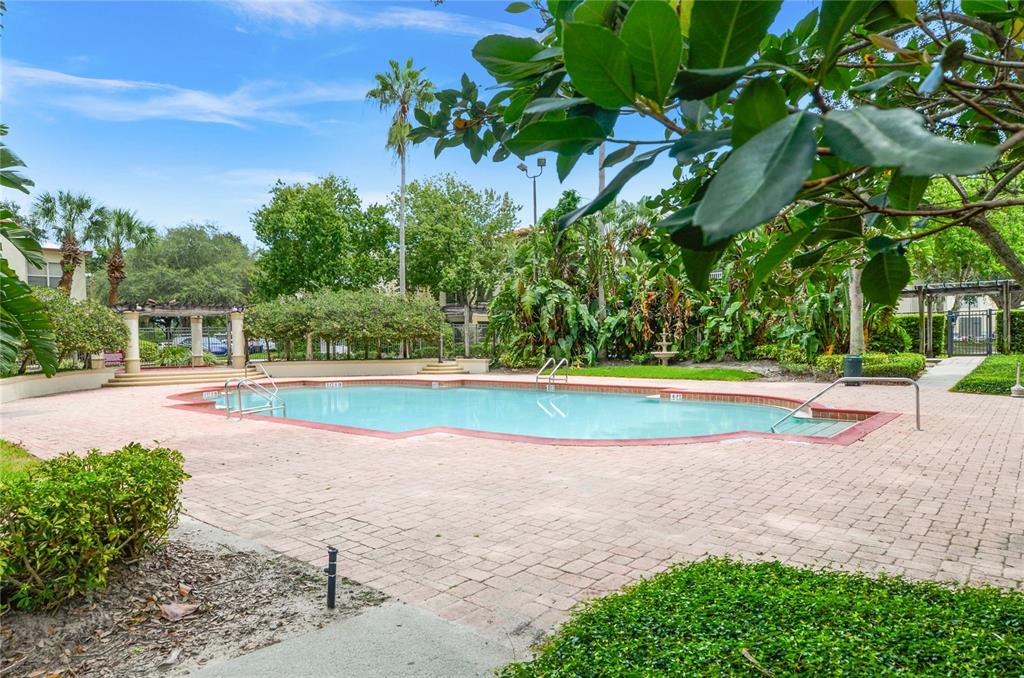 An outdoor swimming pool with a brick deck surrounded by lush landscaping and palm trees — 826 CAMARGO WAY UNIT 302, ALTAMONTE SPRINGS, FL
