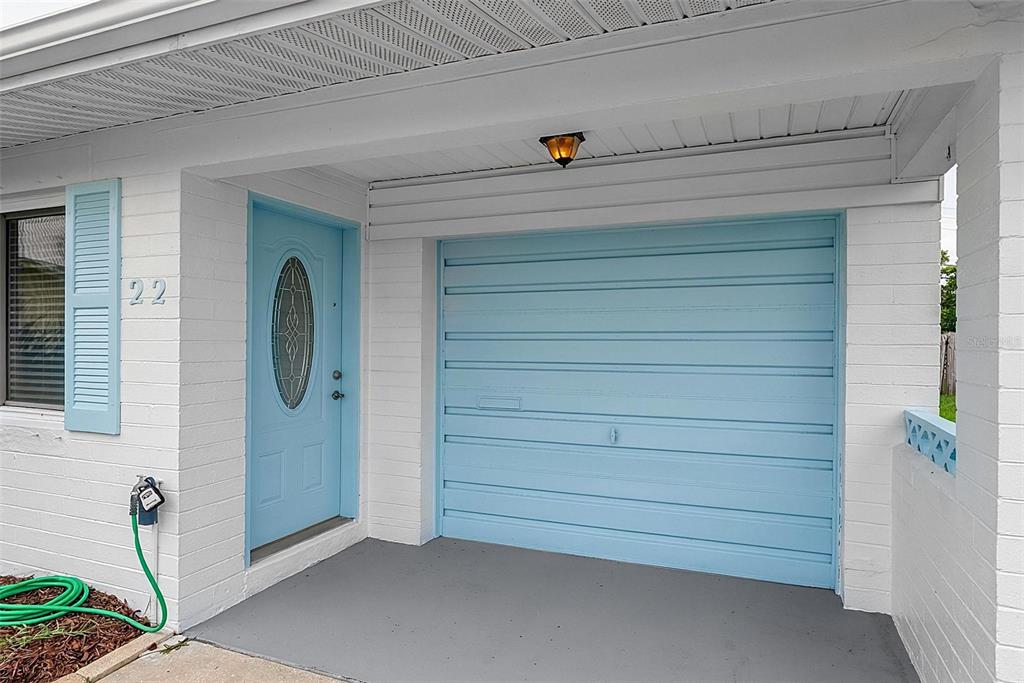 A light blue front door and matching garage door are set into a white brick exterior — 22 BEECHWOOD DRIVE, ORMOND BEACH, FL