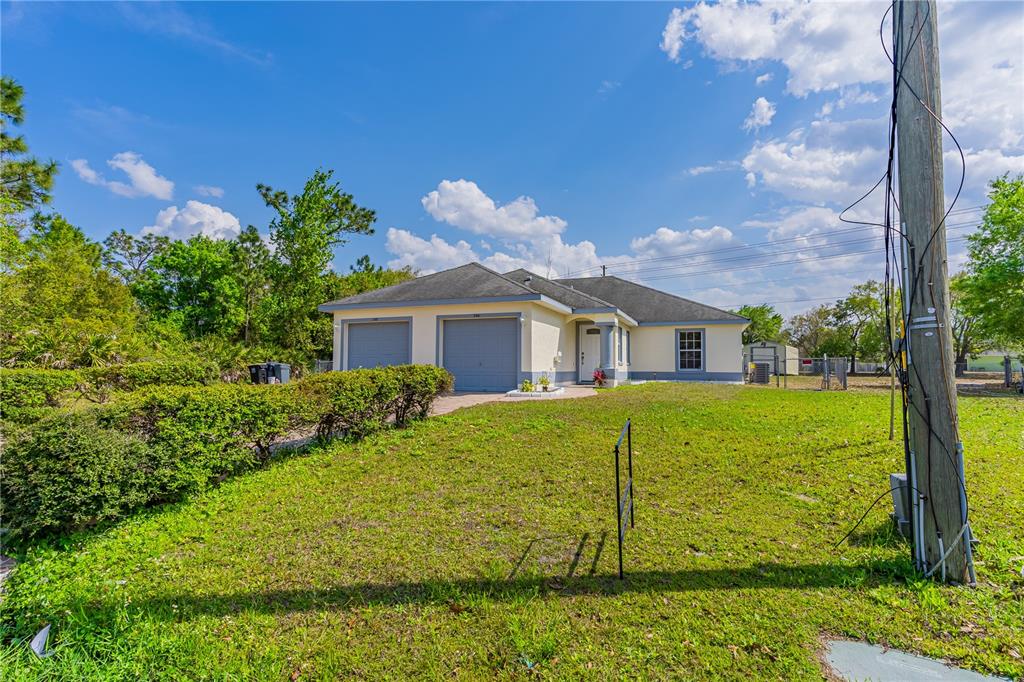 A single-story house with a two-car garage sits on a grassy lot under a blue sky — 746-748 MINK CT, POINCIANA, FL