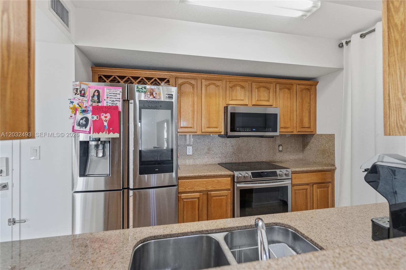 A kitchen features oak cabinets, stainless steel appliances, and tan granite countertops — 4242 NW 2nd St # 1001, Miami FL 33126, MIAMI, FL