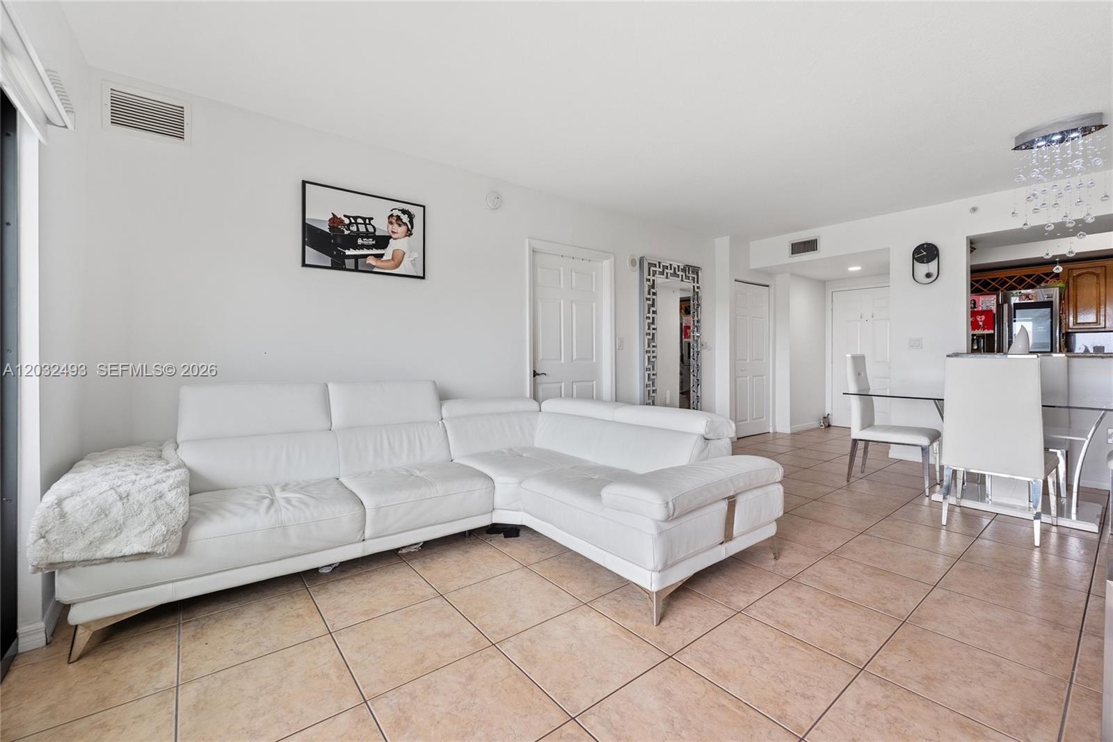 A white sectional sofa sits in a living room with tiled floors and a dining area — 4242 NW 2nd St # 1001, Miami FL 33126, MIAMI, FL