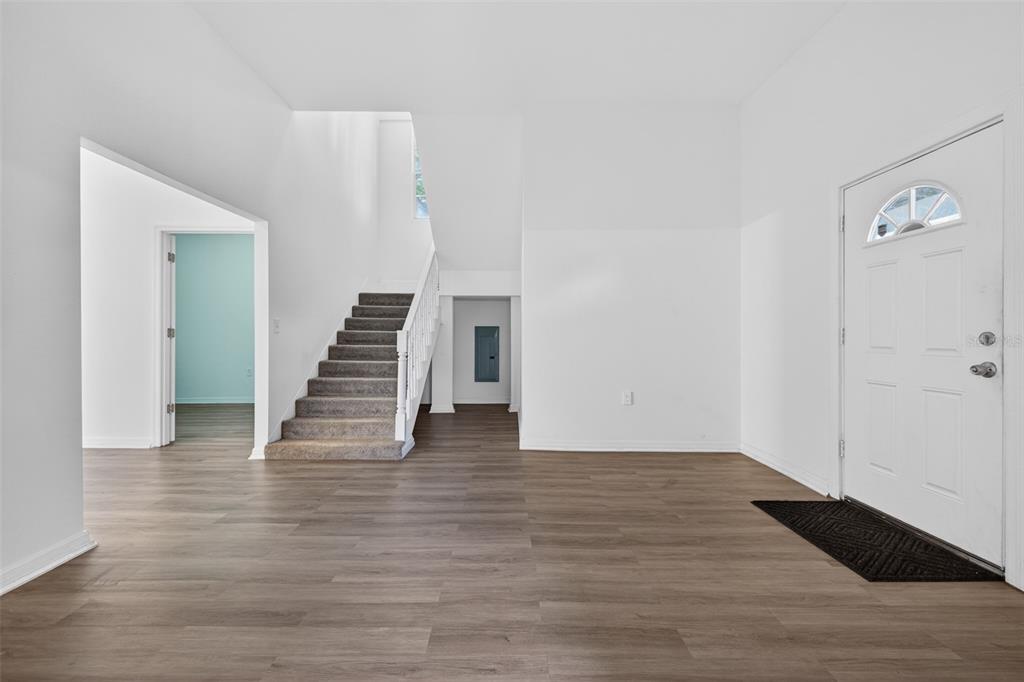An entryway features light wood-look flooring, white walls, a staircase, and a white front door — 105 W COLUMBUS DRIVE, TAMPA, FL