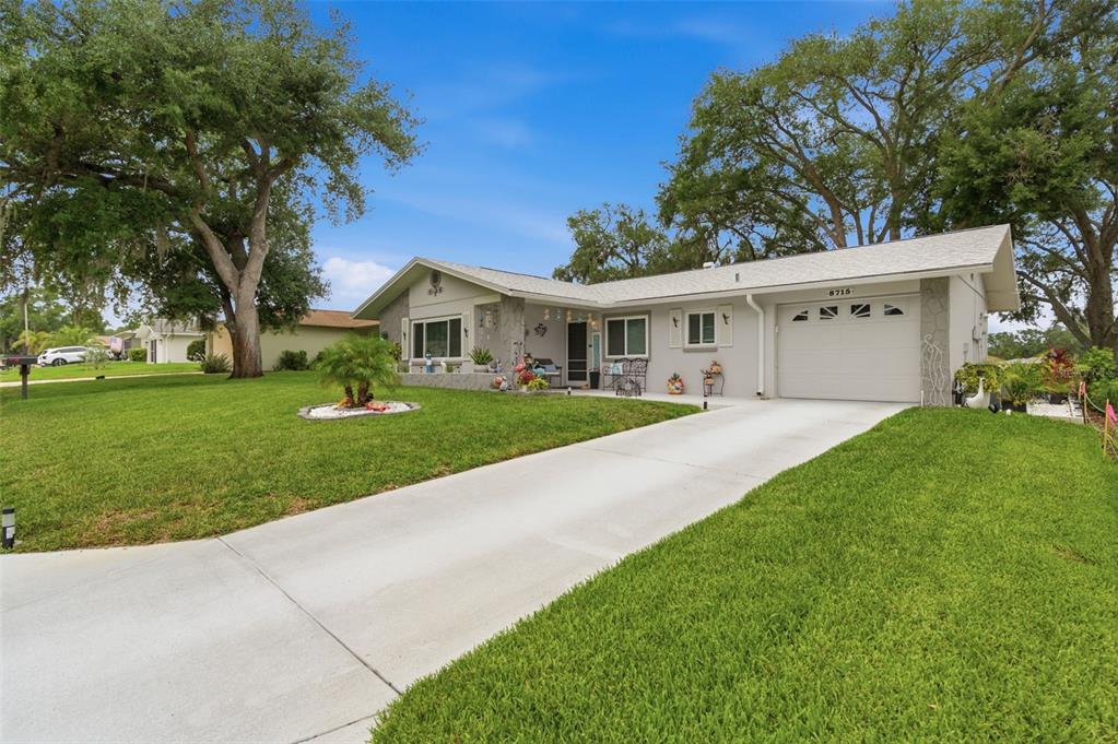 A single-story house with a white garage, gray exterior, and a concrete driveway — 8715 BENTON DRIVE, PORT RICHEY, FL